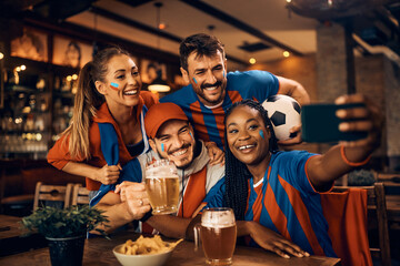 Group of happy soccer fans have fun while taking selfie during world championship in bar.