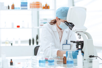 close up. female scientist looking through a microscope.