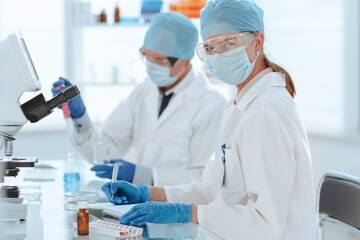 Naklejka premium scientists testing the liquid and writing the results in a laboratory journal.