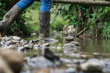 close-up of the feet of a latina girl in blue jeans and black pantaneras boots, crossing a stream....