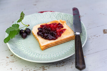 Leckeres Toastbrot mit Johannisbeeren Marmelade auf dem Teller mit Messer