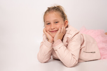 Portrait of a happy smiling cute little girl lying on the floor isolated on white background.