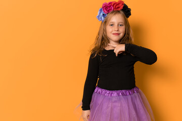 Portrait of child girl in halloween costume isolated on orange background.