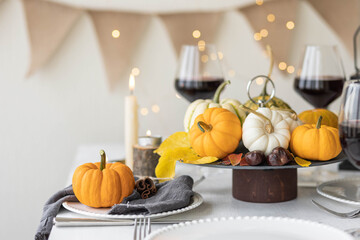 Idea for a beautiful autumn setting for thanksgiving family dinner or wedding. Orange pumpkin as decor. Cozy fall home atmosphere.