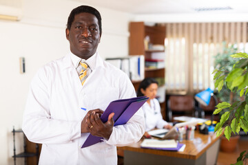 Obraz premium Portrait of friendly male doctor wearing uniform with folder