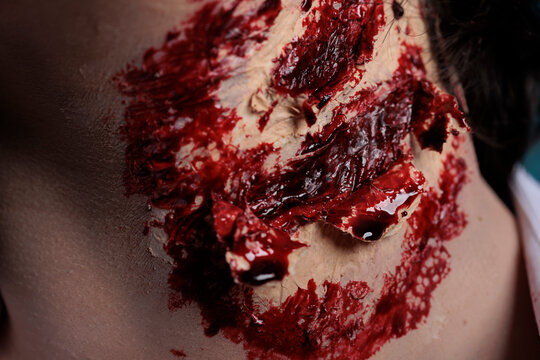Dangerous demon with blood on wounds, having ugly scary scratches on neck in studio. Brain eating cruel zombie having dirty scars on wounded body, apocalyptic and aggressive monster. Close up.