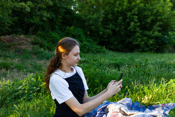 a woman is resting in a clearing photographing a view on a smartphone