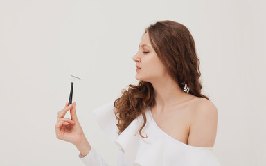 a beautiful woman on a light background holds a razor in her hand and looks at her