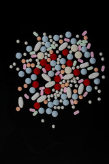 several colored pills on a black background