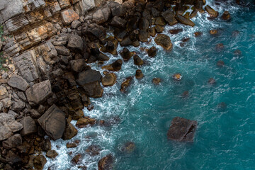top view of the rocky coast in a storm, azure water and waves near the shore