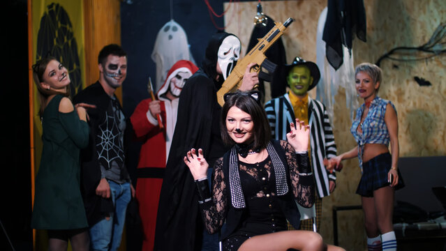 Halloween party, photo session, young people dressed up in scary costumes and made a horrific make-up. they are having fun, in the background Halloween scenery is seen. High quality photo