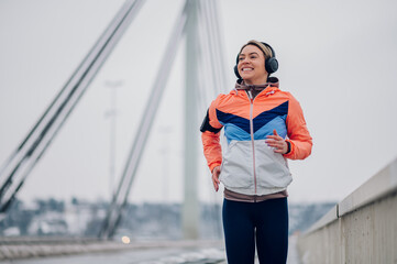 Obraz premium Woman running on the bridge at winter and snow.