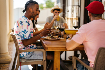 black man with braided hairstyle eating at a table with friends