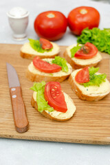 Bruschetta sandwich bread toast with soft white cheese ricotta,fresh tomatoes,basil greenery on a wooden cutting board.Tasty healthy vegetarian food,Italian cuisine appetizer. top view flat lay