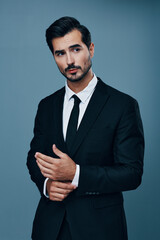 Business man in business suit businessman poses on blue background adjusts suit and looks into camera front view