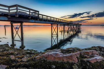 Pier leads into sea sunset with refelction