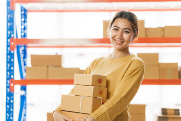 Young pretty asian entrepreneur warehouse worker working and checking product inventory in warehouse showroom.