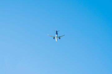 the plane is flying against the blue sky