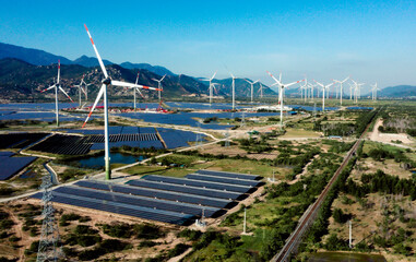 Solar panels and wind turbines generating alternative power and green renewable energy with blue sky background. Clean energy concept. Sustainable growth and climate change prevention.