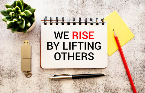 Motivation concept.Text WE RISE BY LIFTING OTHERS writing on notebook.