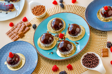 Chocolate round cake with raspberry set on a blue plate on a light background.Berry dessert.Delicate airy cake souffle.Appetizing cupcakes and pastries.