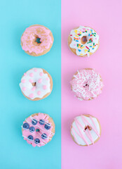 Creative pattern of colorful donuts on pastel blue and pink background. Minimal food concept. Isometric