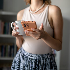 One woman standing in the office drinking coffee and use mobile phone