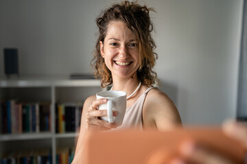 One woman standing in the office drinking coffee and make video call