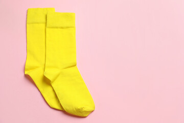 Yellow socks on light pink background, top view. Space for text