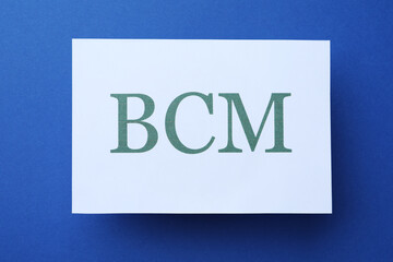 White paper with abbreviation BCM (Business Continuity Management) on blue background, top view