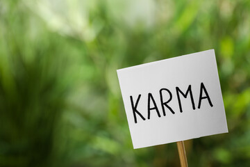 Sign with word Karma on blurred background, closeup. Space for text