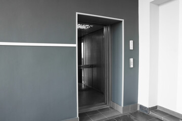 Open elevator`s cabin with big mirror in hall