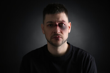 Obraz premium Man with facial injuries on dark background. Domestic violence victim