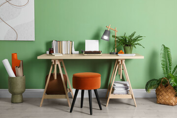 Writer's workplace with typewriter on wooden desk near pale green wall in room