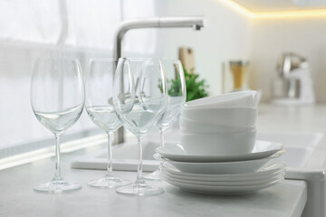 Different clean dishware and glasses on countertop near sink in kitchen