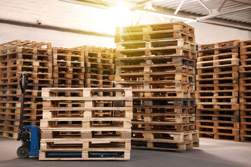 Modern manual forklift and wooden pallets in warehouse - obrazy, fototapety, plakaty