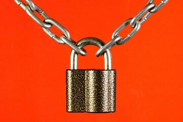 The chain is connected by a lock, on a red background. The concept of securing or connecting something.