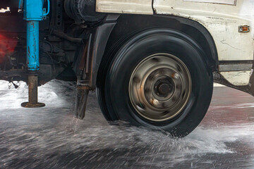 Detail of the wheel of a truck driving in the puddle on a wet road.