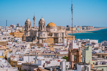 Obraz premium Rooftops of houses in aerial view of the medieval city of Cádiz and towers and cupula of Cathedral de la Santa Cruz in seafront, SPAIN
