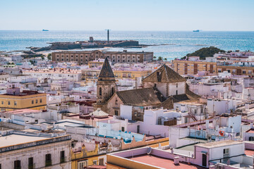 Fototapeta na wymiar Roofs of the city of Cádiz with tower of San Lorenzo church and San Sabastian castle on the sea in the background, SPAIN