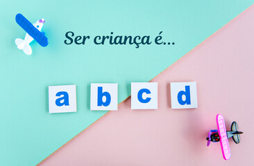 plastic airplane toys and alphabet letters on green and pink background