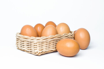 eight chicken eggs in a rattan basket on white background