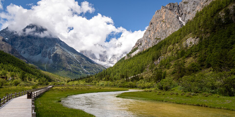 Fototapeta na wymiar Daocheng Yading scenery- S shape river and mountains covered with clouds. The scenic spot is located in Daocheng, Sichuan, China. Panorama
