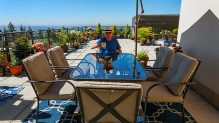 Senior enjoying coffee and retirement in comfortable isolation on a mountain-top penthouse patio...