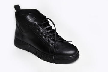 Defocus one black leather male shoe, white background. Men’s ankle boot leather isolated on white background, closed up. Winter boots. Out of focus