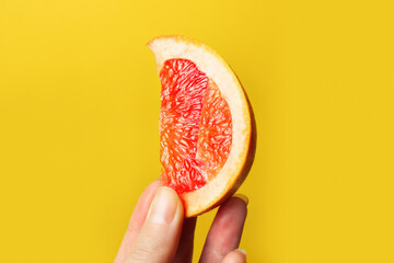 Defocus female hand holding piece of a red grapefruit. Healthy food concept. Fresh orange juice....