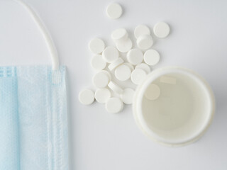 Tablets with a tube and a medical mask on a white background. Closeup