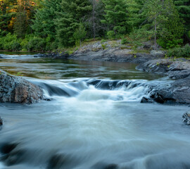 The top of the waterfall at Chutes Provincial Park, simply known as The Chutes, cascades rapidly towards the main falls surrounded by forest in Massey, Ontario.