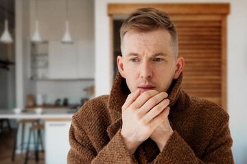 a man in a warm coat trying to keep warm at home. Home heating shutdown concept. Gas shutdown.