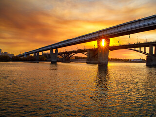 The world's largest metro bridge on v-shaped concrete supports across the Ob river and road October bridge, the big city Novosibirsk at sunset